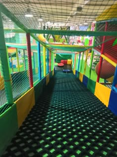 an indoor play area for children with colorful walls and nets on the ceiling, along with slides