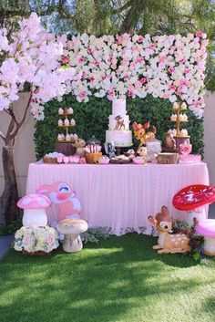 a table topped with lots of food and desserts next to a wall covered in flowers