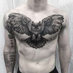 a man with an owl tattoo on his chest is standing in front of a white backdrop