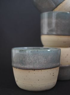 three gray and white bowls stacked on top of each other in front of a black background