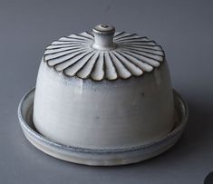 a white ceramic dish with a lid on the bottom and a silver rim around it