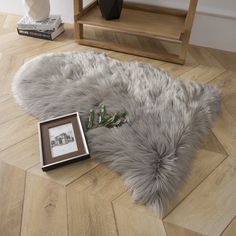 a white sheepskin rug on the floor next to a framed photo and an empty frame