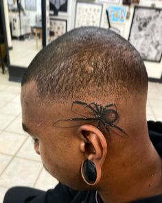 a man with a spider tattoo on his forehead and ear piercings in front of him