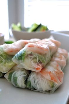 shrimp and vegetable spring rolls on a white plate with dipping sauce in the bowl behind them