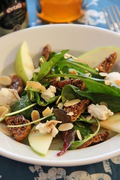 a white bowl filled with spinach, apples and other food on top of a table