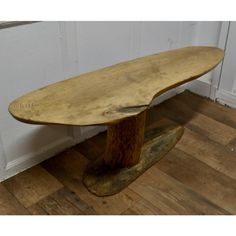 a wooden bench sitting on top of a hard wood floor next to a white wall