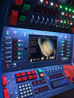 a control panel with an image of saturn on the screen and other electronic equipment around it