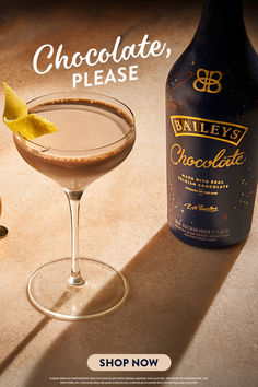 a bottle of bailey's chocolate syrup next to a martini glass with an orange peel in it