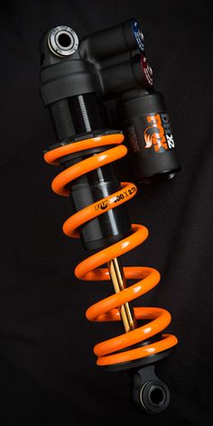 an orange coiled shock spring on the front of a vehicle's suspension system