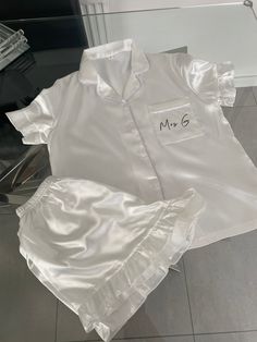 a white shirt and shorts are sitting on the floor next to a glass case with a name written on it