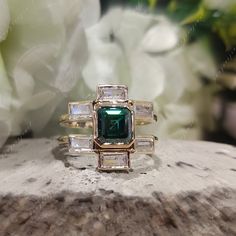 a green ring sitting on top of a piece of wood next to white flowers and greenery