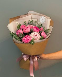 a person holding a bouquet of pink flowers