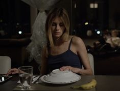 a woman sitting at a table in front of a plate with a banana on it