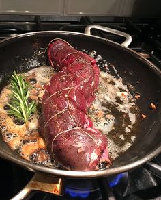 two raw meats are cooking in a pan on the stove top with spices and herbs