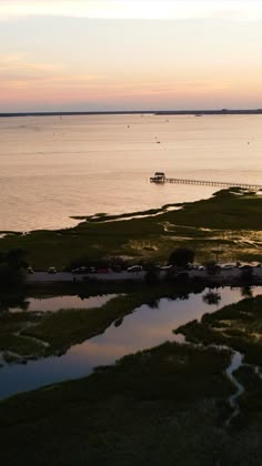 the water is calm and there are boats out in the distance on the lake at sunset