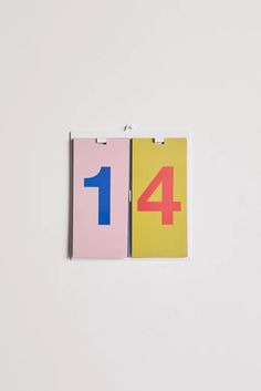 two pieces of colored paper with the number one on them are hanging on a white wall