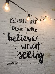 a white brick wall with some lights on it and the words, blessing are those who believe