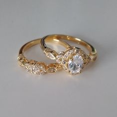 two gold wedding rings with diamond accents on each one and an engagement ring in the middle