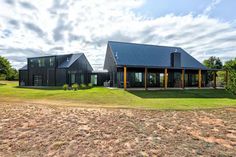 a large black house sitting on top of a lush green field