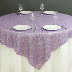 a purple table cloth with silver sequins is set on top of two white plates