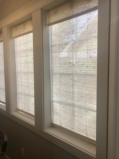 three windows with white blinds in a room