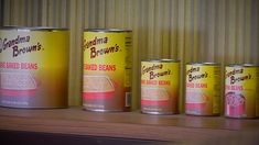 three cans of brown's breaded beans sit on a shelf