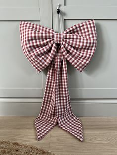 a red and white gingham bow hanging from the side of a wooden door