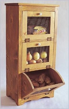 a wooden cabinet with three compartments filled with fruits and vegetables, including an egg carton