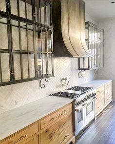 a kitchen with wooden cabinets and white marble counter tops, an oven top and range hood