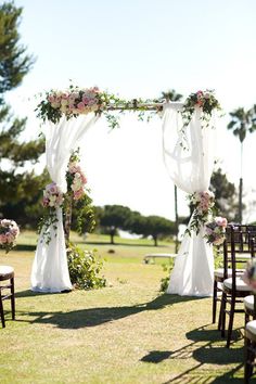 an outdoor wedding setup with white drapes and pink flowers