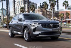 a silver buick suv driving down the road with palm trees in the backgroud