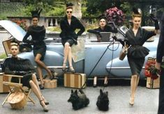 a group of women sitting on top of suitcases in front of a car