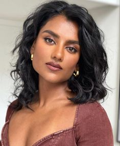 a close up of a person wearing a brown shirt and gold hoop earrings on her left ear