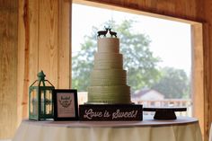 a wedding cake sitting on top of a table next to a lantern and framed pictures