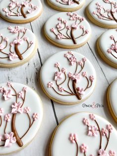 cookies decorated with pink and brown icing are arranged on a white surface, along with flowers