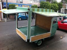 a small green and white cart parked on the side of a road next to a red car