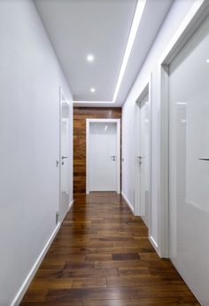 an empty hallway with wooden floors and white walls