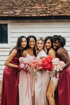 the bridesmaids pose for a photo with their bouquets in front of a white house