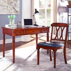 a wooden desk with a laptop on top of it next to a chair and lamp