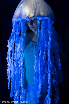 a woman wearing a blue jellyfish costume in the dark with her hands on her hips