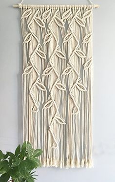 a macrame wall hanging next to a potted plant on top of a table