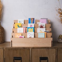 there are many greeting cards on the top of this wooden box and two vases next to it