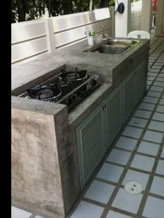 an outdoor kitchen with two stoves on the counter and one sink in the middle