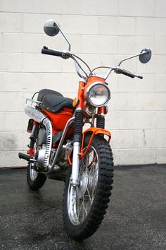 an orange motorcycle parked in front of a white wall