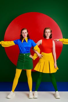 two young women are posing in front of a red and green background