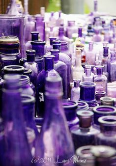 many purple glass bottles are lined up together