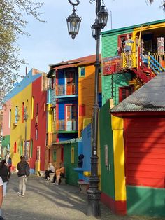 people are walking down the street in front of colorful buildings