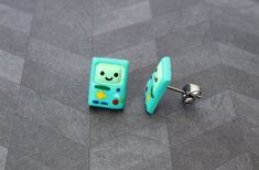 a pair of blue and green square shaped cufflinks with faces on them sitting on the floor