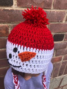 a child wearing a red and white crocheted hat with a snowman on it