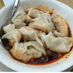 a bowl filled with dumplings sitting on top of a table next to a fork